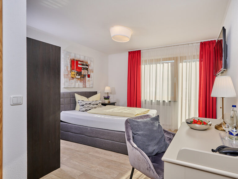 Ein gemütliches Einzelzimmer Donau mit einem komfortablen Bett und stilvollem Schreibtisch.