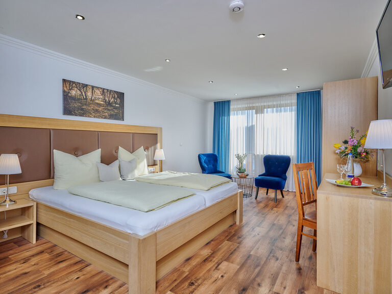 Ein großzügiges Bett auf Holzböden im Doppelzimmer Donau mit Balkon.