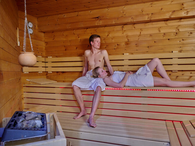 Junges Paar in Sauna-Tüchern beim Entspannen im Wellnessbereich des Hotel zum goldenen Anker